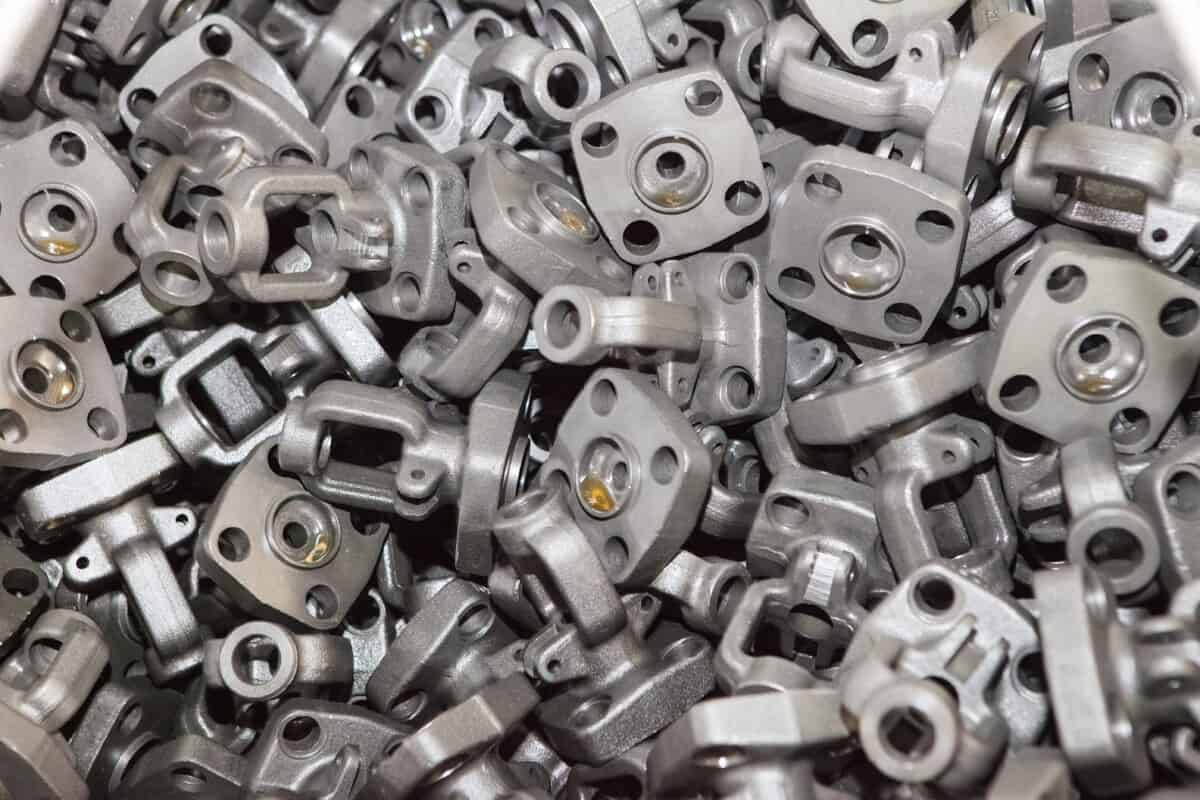 A close-up, high-angle view of a large pile of randomly assorted, heavy laminated steel parts, demonstrating a complex challenge for robotic bin picking and the need for a precise AI vision solution.