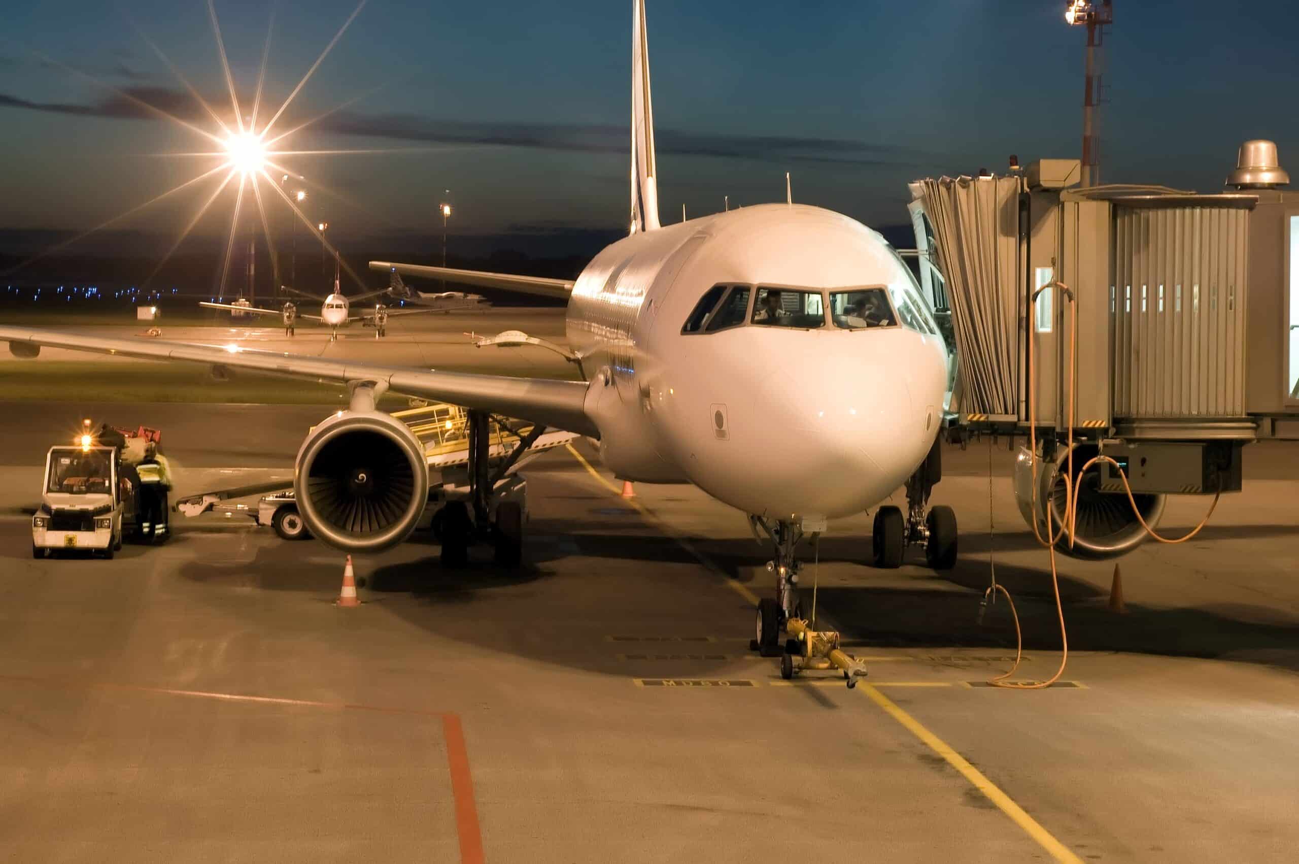 Airport Apron Management commercial airplane on an airport apron at night connected to jet bridge