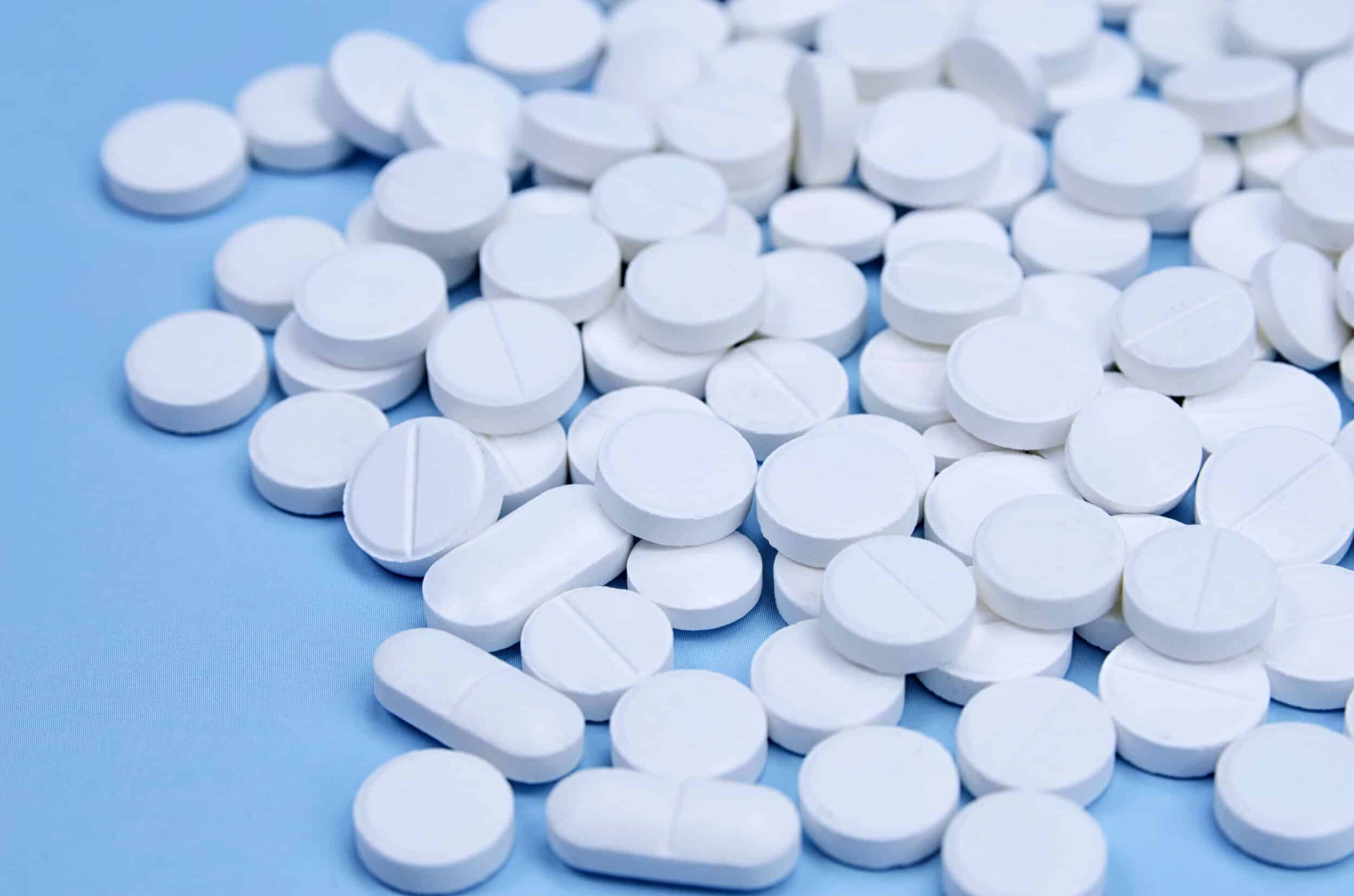 newly produced white pills on a blue surface