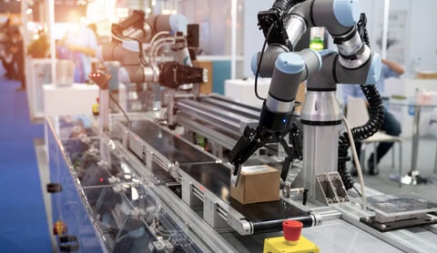 Universal Robots UR5 Collaborative Robot Universal Robots UR5 Collaborative Robot on a production line placing a small cardboard box onto a conveyor belt