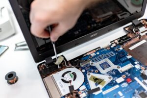 Worker performing assembly verification on a laptop, representing precision assembly in electronics manufacturing.