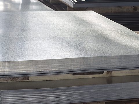 A wide-angle view of a large stack of raw metal sheets on a pallet, symbolizing the raw materials and inventory used in the metal processing and manufacturing industry.