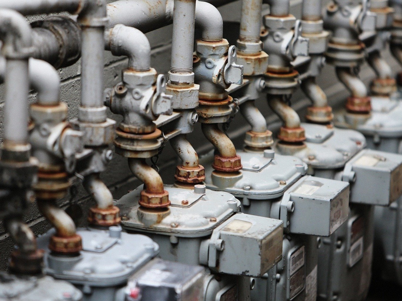 Close-up of a row of interconnected industrial gas meters and pipes, demonstrating the use of AI vision for infrastructure inspection, leak detection, and automated gauge reading in the public utilities industry.